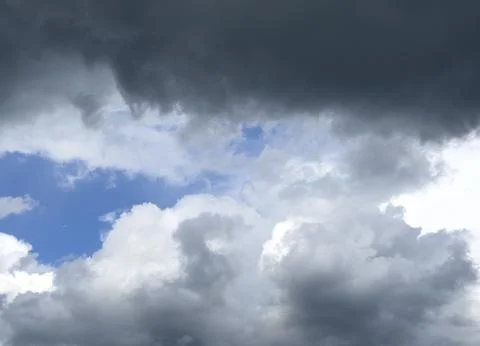 Dark storm cloud hangs above lighter clouds in blue sky. Dramatic contrast .. 스톡 사진