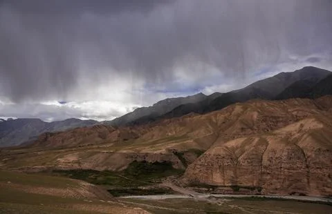 Dark storm cloud over mountain range and valley in Asia. Stock Photos