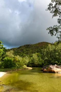 Dark storm cloud over pool at anse lazio Stock Photos