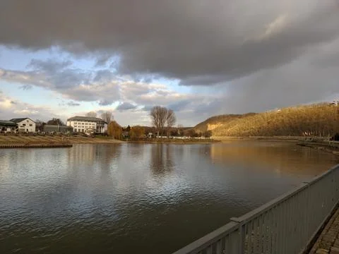 Dark storm clouds above the smooth water of the river moselle in Germany Stock Photos