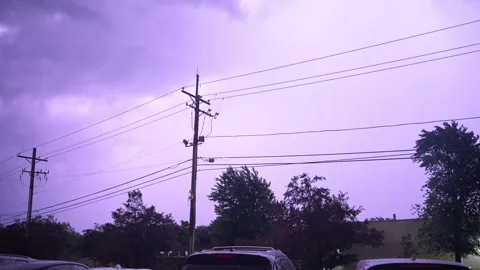 Dark storm clouds and lightning illuminating the night sky above power lines Vídeos de archivo 347574948