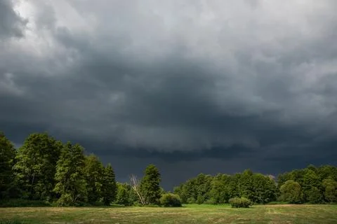 Dark Storm Clouds and Shelf Cloud Approaching Green Meadow and Forest Landsca Stock Photos