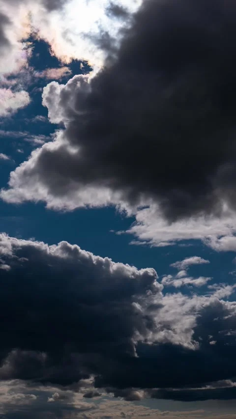 Dark storm clouds drift rapidly across a deep blue sky as the sun shines th.. 스톡 동영상 337457035