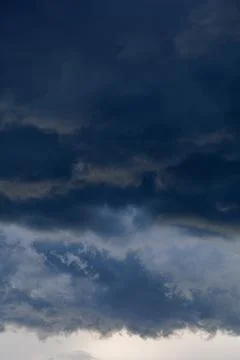 Dark storm clouds forming before heavy rain in dramatic sky, bad weather and nat Stock Photos