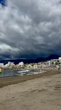 Dark storm clouds gather above Playa de las Americas on Tenerife while Atlant Stock Photos