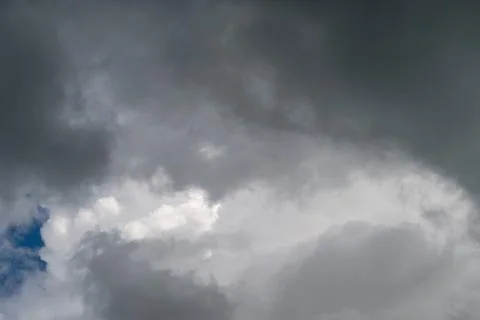 Dark storm clouds gather above horizon, heavy gray layers, isolated patch o.. Stockfoto's