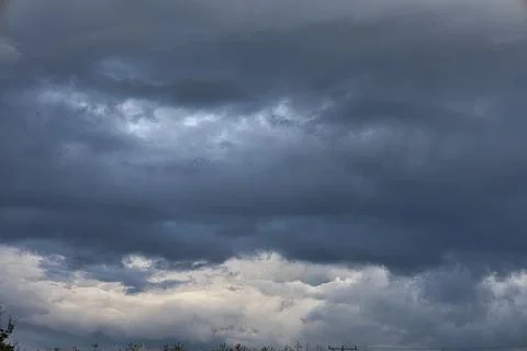 Dark storm clouds gather ominously in the sky, hinting at impending rain Stock Photos