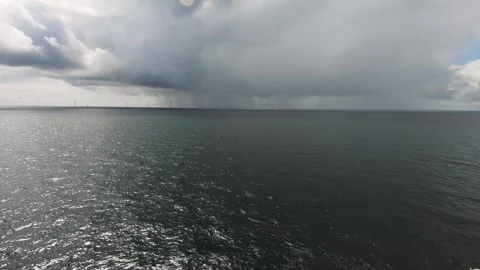 Dark storm clouds gather over the open sea as sunlight reflects off the water Stock Footage 321641554