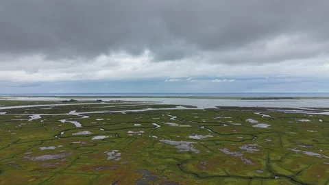 Dark storm clouds gather over vast Ipswich salt marsh, winding tidal channels Stock Footage 345699572
