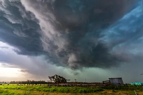 Dark storm clouds gather over expansive rural farmland Stock Photos