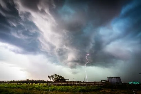 Dark storm clouds gather over expansive rural farmland Stock Photos