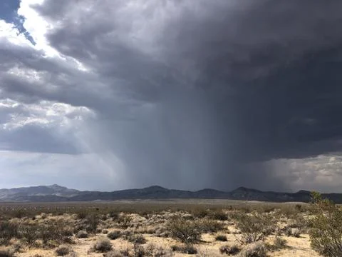 Dark Storm Clouds Gather Over Dry Desert Landscape Before the Rain Falls Stock Photos
