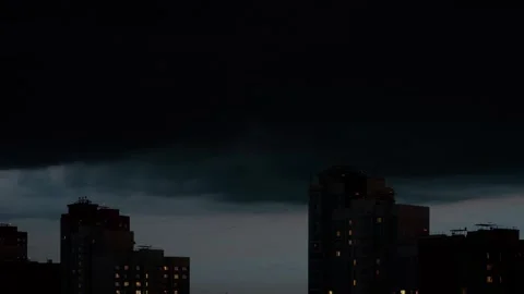 Dark storm clouds gathering over city buildings at night 動画素材 311869648
