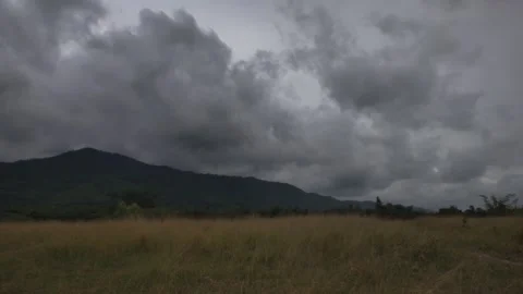 Dark Storm Clouds Gathering Over Mountain and Golden Grass Field Stock Footage 342952476