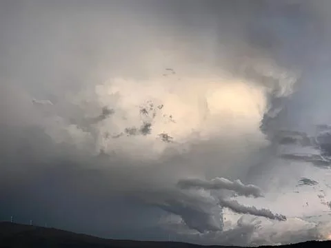 Dark storm clouds gathering in the sky over hills Stock Photos