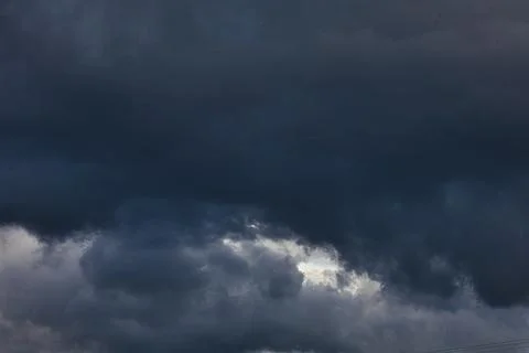 Dark storm clouds gathering in the sky with a break of light Stock Photos