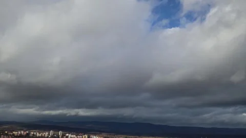 Dark storm clouds loom over a distant mountain range and a small town below, wit Stock Footage 300540738
