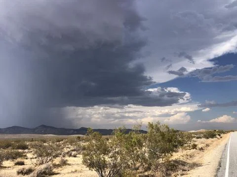 Dark Storm Clouds Loom Over a Desert Landscape With Distant Mountains Stock Photos