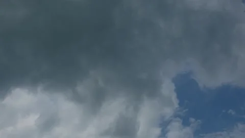 Dark storm clouds moving across bright blue sky in timelapse Stock Footage 332790367
