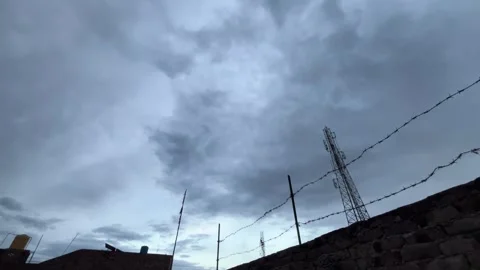 Dark Storm Clouds Over Barbed Wire and Cell Tower Видео 332369422