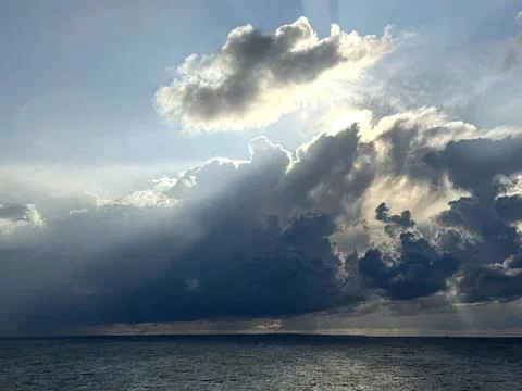 Dark storm clouds over calm ocean water under cloudy sky Stock Photos