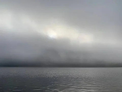 Dark storm clouds over calm water with a cloudy sky Stock Photos