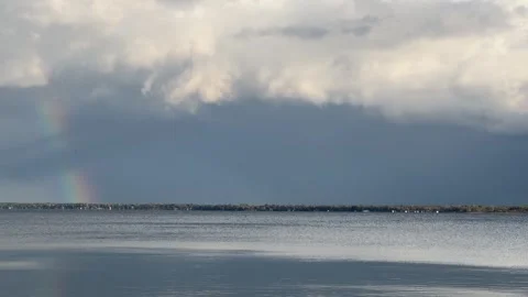 Dark storm clouds over a large lake with rainbow Video stock 273176516