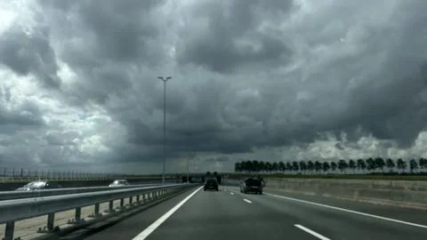 Dark storm clouds over modern highway with cars driving toward tunnel, guarded Fotos Stock