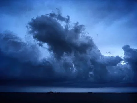 Dark storm clouds over the ocean with a ship in distance Stock Photos