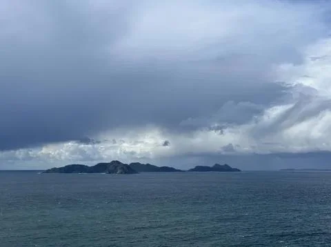 Dark storm clouds over the ocean with distant islands Stock Photos