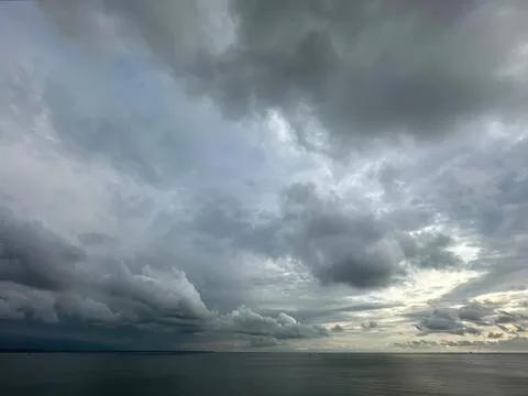 Dark storm clouds over the ocean with heavy rain forecast Stock Photos