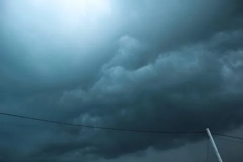 Dark storm clouds over power lines and electrical poles low angle view Stock Photos