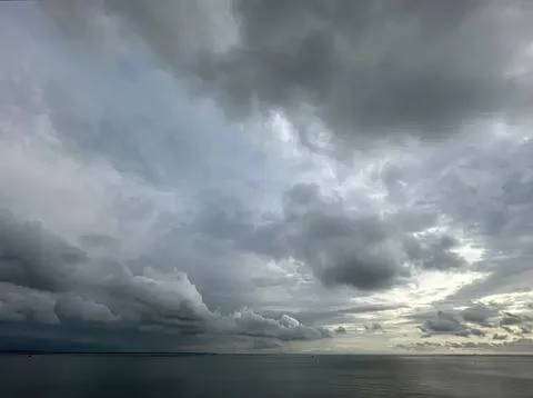 Dark storm clouds over water with cloudy sky Stock Photos