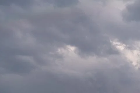 Dark storm clouds roll low with heavy textures and muted light, building tens 写真素材
