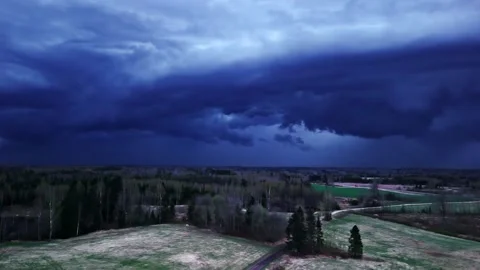 Dark storm clouds rolling over a rural landscape, creating a dramatic weather Stock Footage 333998660