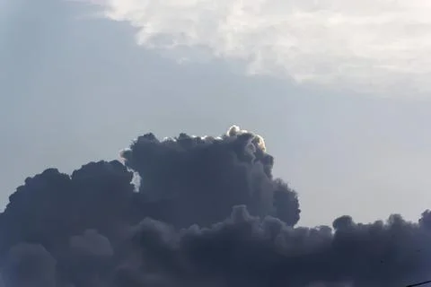 Dark storm clouds in the sky with sunlight peeking through Stock Photos
