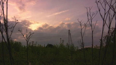 Dark storm clouds time lapse with electric pylon at sun set Stock Footage 77189572