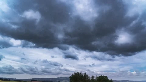Dark stormy clouds move above the rural landscape carried by the strong Stock Footage 284736821