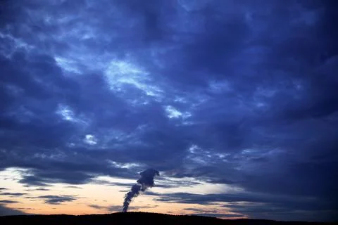 Dark stormy sky sunset clouds with smoke coming from pipe Stock Photos
