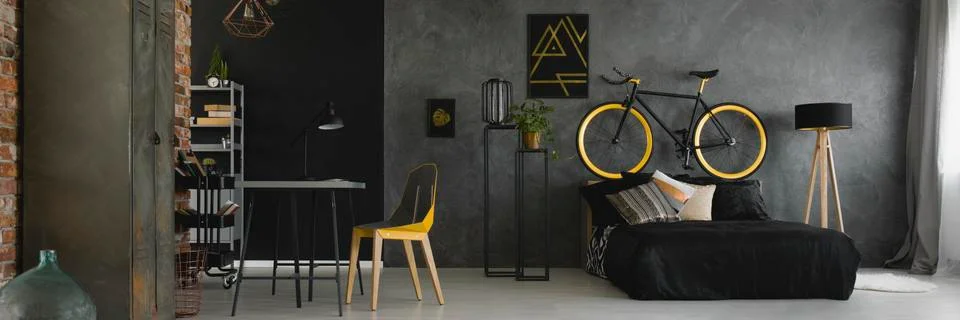 Dark studio flat interior with texture grey wall, black and yellow bike stand Stock-Fotos