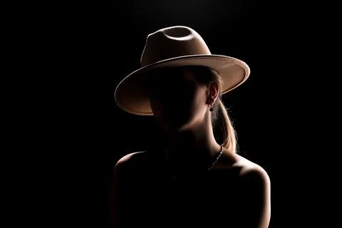 Dark studio portrait of young elegant sexy woman with a white hat and white.. Stock Photos
