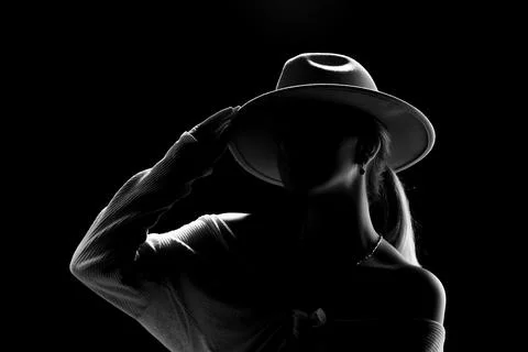 Dark studio portrait of young elegant sexy woman with a white hat and white.. Foto stock