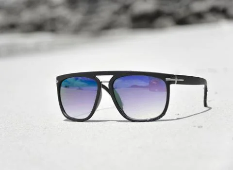 Dark sunglasses on the sand with black frames. 스톡 사진