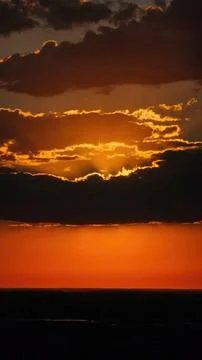 Dark sunset over a calm ocean with orange and yellow clouds Foto stock
