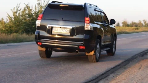 Dark SUV car driving through empty road at sunset at countryside birds eye view Stock Footage 115118734