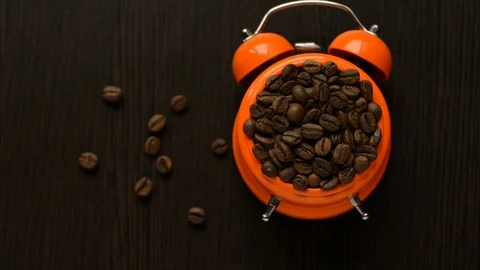 On a dark table, an alarm clock rings with coffee beans falling down Stock Footage 106006184