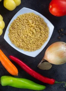 Dark table background of cooking. Grain and vegetables . Top view. Photos