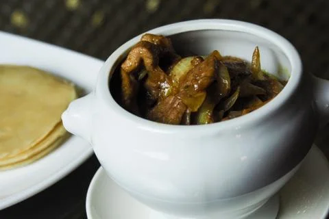 On the dark table is a pot of pork cooked in curry sauce Stock Photos