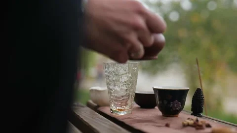 Dark tea is poured from a clay teapot into a glass dish. Chinese tea ceremony Stock Footage 229861087
