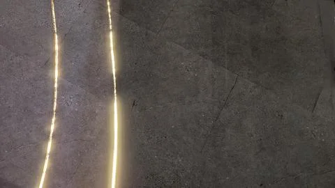 A dark, textured ground surface with two parallel yellow light strips glowi.. 스톡 사진